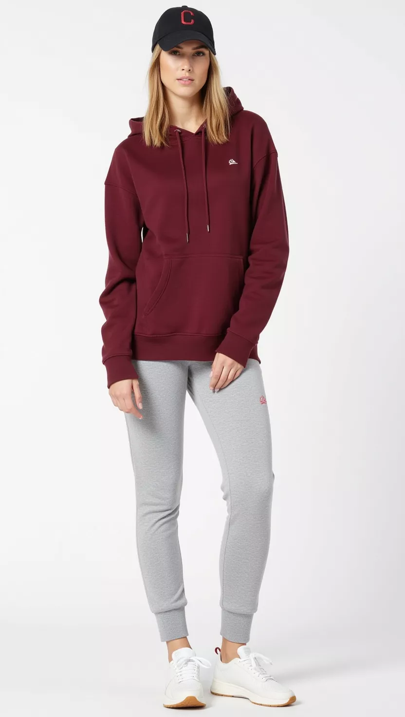 A beautiful woman in a maroon oversized hoodie, gray fleece joggers, clean white athletic sneakers, and a black baseball cap, with a casual, comfortable expression.