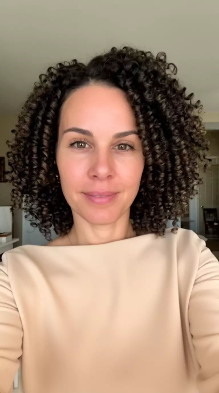 selfie of a 37-year-old woman wearing a beige boat neck top with finger-coiled curls