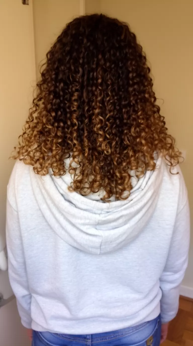 casual photo of a 33-year-old woman wearing a light gray hoodie with butterfly layered curls, back view
