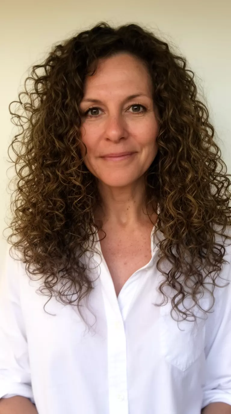 casual photo of a 43-year-old woman wearing a white button down with loose bouncy ringlets