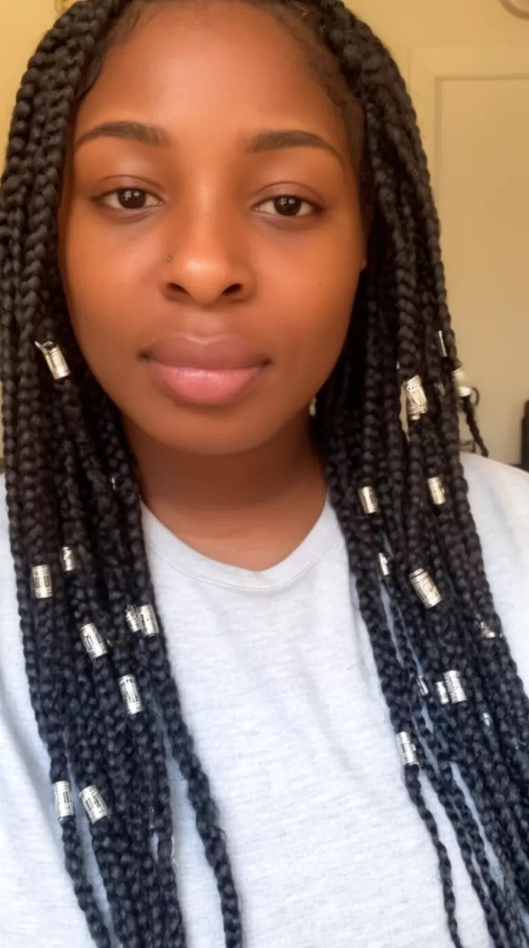 casual close-up photo of a 27-year-old black woman wearing a light gray top with mid-length box braids decorated with silver cuffs
