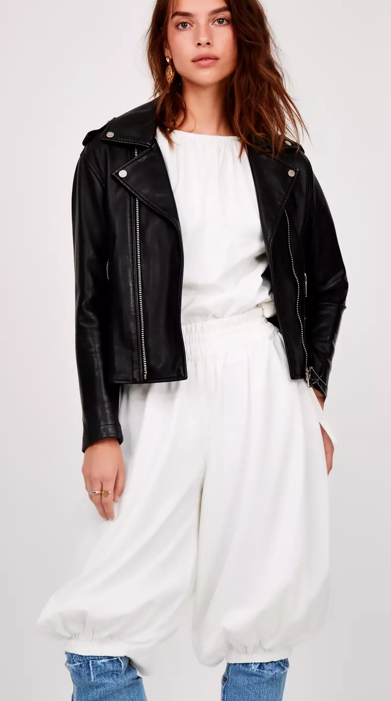 A beautiful woman in cloud white balloon pants, cloud white puff sleeve blouse, black faux leather jacket, and blue jeans base.