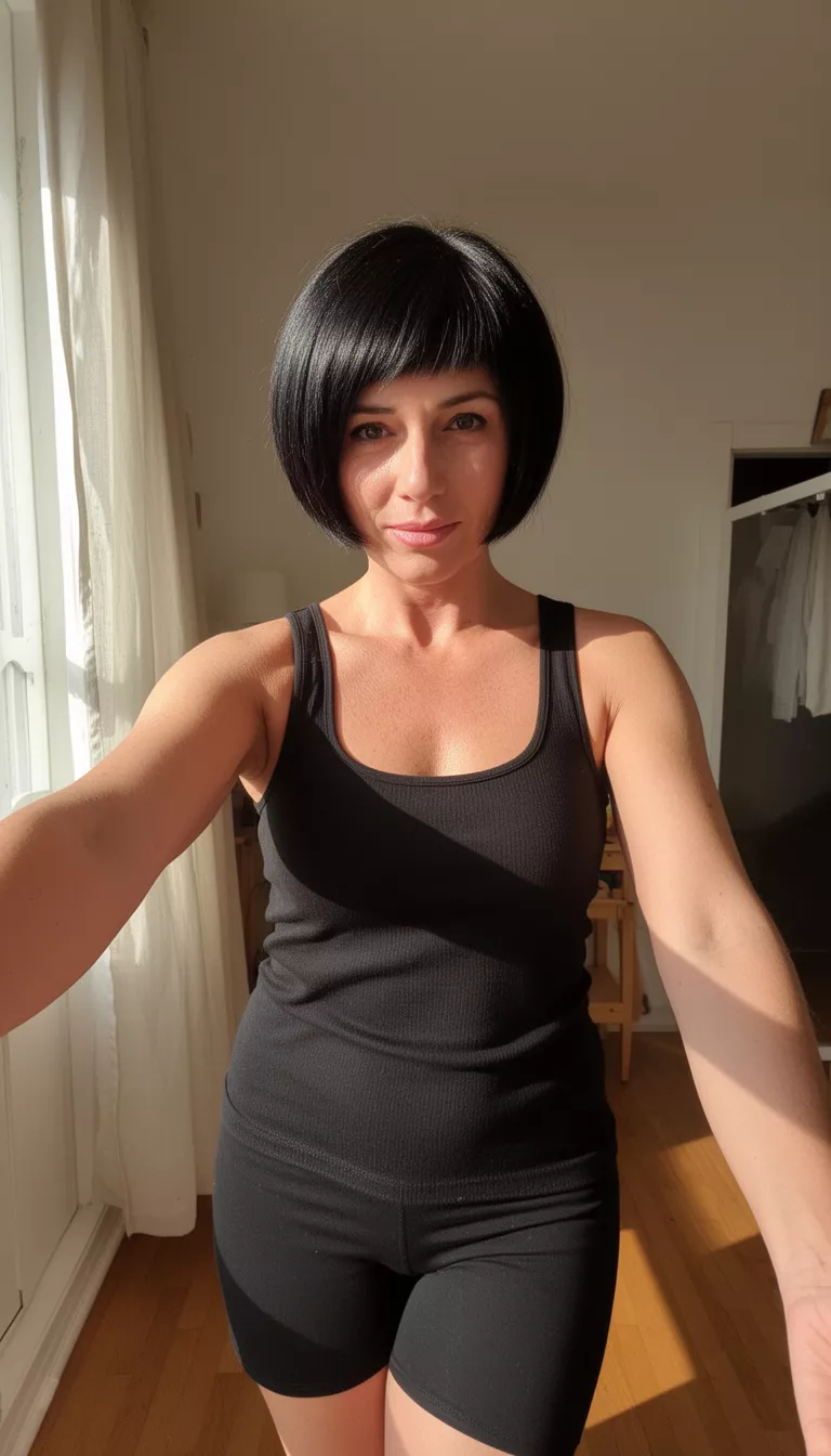 selfie of a 41-year-old woman wearing a black tank top with a black colored short, sleek bob hairstyle, front view, indoors with sunlight.