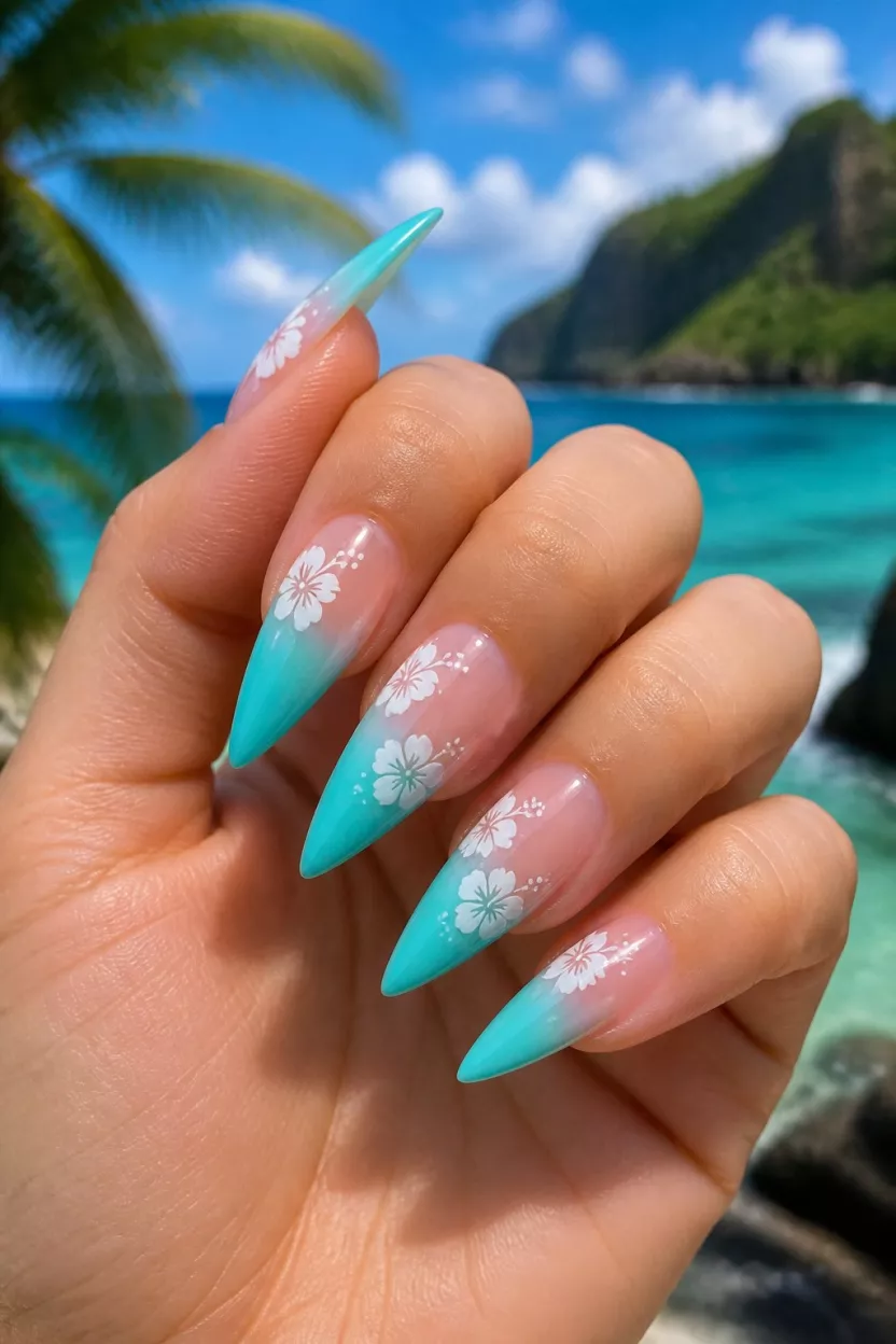 close-up shot of a woman’s hand with five fingers showing nails with stiletto nails featuring white hibiscus flowers and turquoise and white French tips with a strong gradient, island setting background.