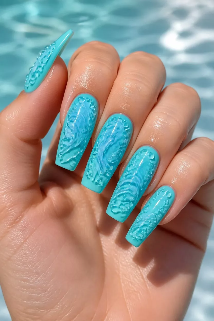 close-up shot of a woman’s hand with five fingers showing nails with coffin-shaped nails painted bright turquoise with raised clear bubbly and swirling 3D wave designs, aquatic theme.