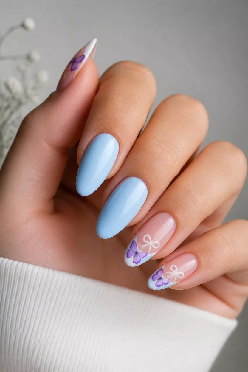 close-up shot of a woman’s hand with five fingers showing nails with light blue solid nails and sheer French tips with purple butterflies and small white bows, soft natural background.