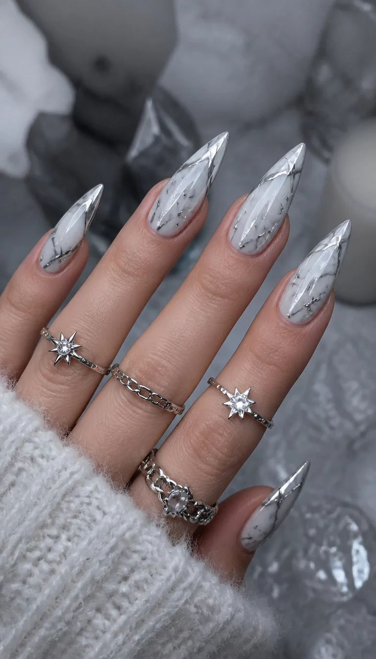 close-up shot of a woman’s hand with five fingers showing stiletto nails with a marble-like white and silver design, accented with small stars, multiple silver rings are worn, cold aesthetic background.