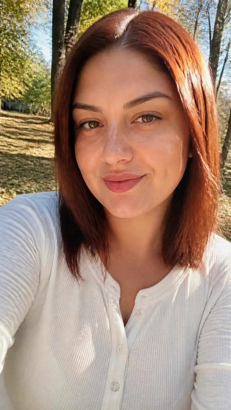 selfie of a 28-year-old Mediterranean plus size woman with a chubby face, olive, straight nose, straight eyebrows, and full lips. Her face features dimples, light freckles, and subtle natural facial asymmetry. She has almond-shaped hazel eyes, pronounced cheekbones, subtle smile, thoughtful. She is slim and is wearing a white henley shirt with spiced cider auburn sleek straight bob hair, bright natural daylight, outdoor fall background