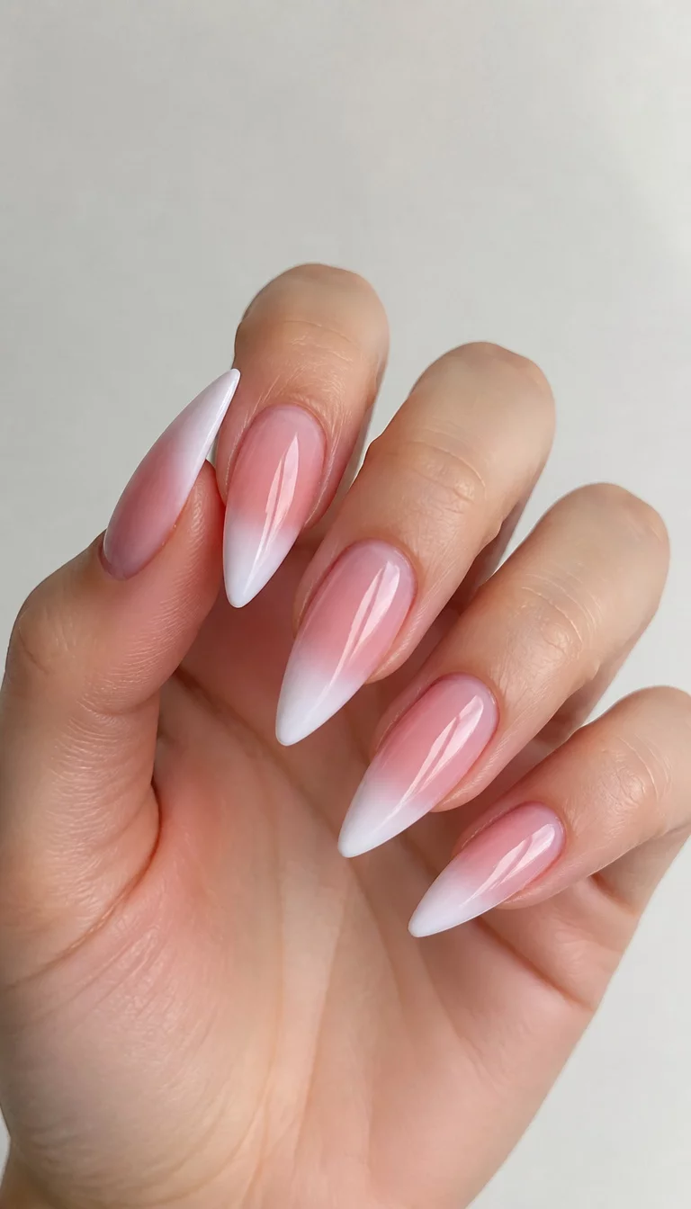 Soft Stiletto Pink Transitions close-up shot of a woman’s hand with five fingers showing sheer pink gradient stiletto nails with soft white tips and a natural transition, clean minimalist background.