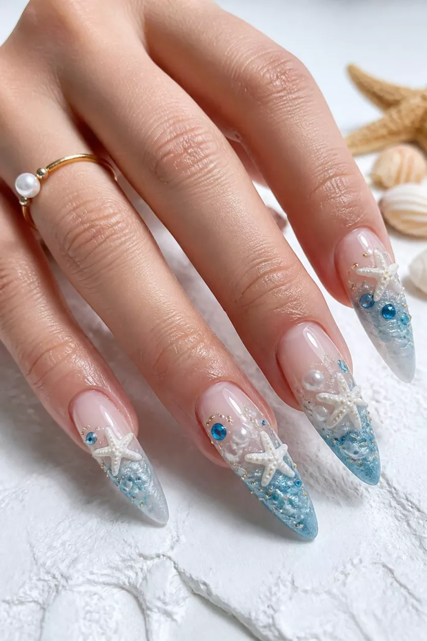 close-up shot of a woman’s hand with five fingers showing nails with elegant, long stiletto nails adorned with 3D white starfish, pearls, and blue gems over a pale blue and white wave design, bright white textured foreground.