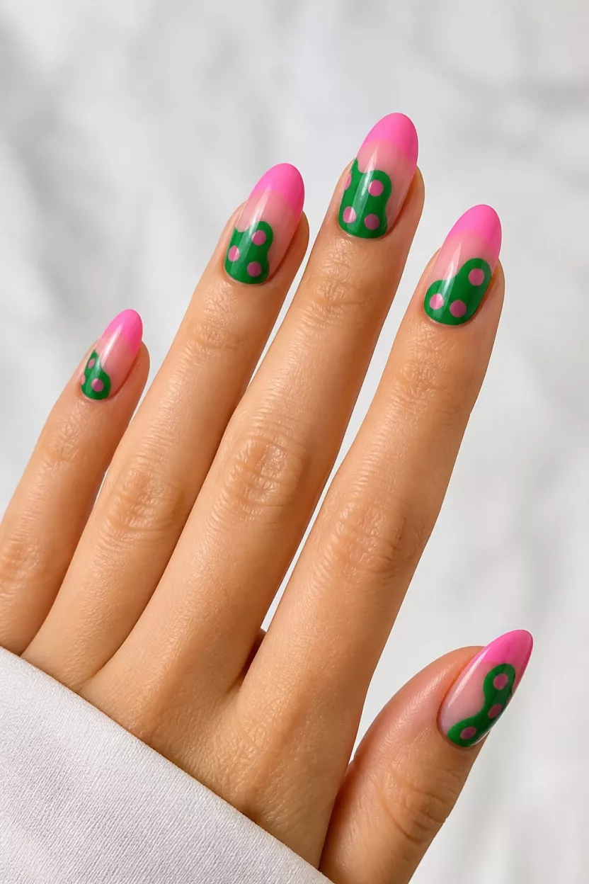 Abstract Green And Pink Ombre close-up shot of a woman’s hand with five fingers showing long oval nails featuring a bright pink-to-nude ombré with large, irregular green shapes with pink dots, creating an abstract, glossy look, over a light background.