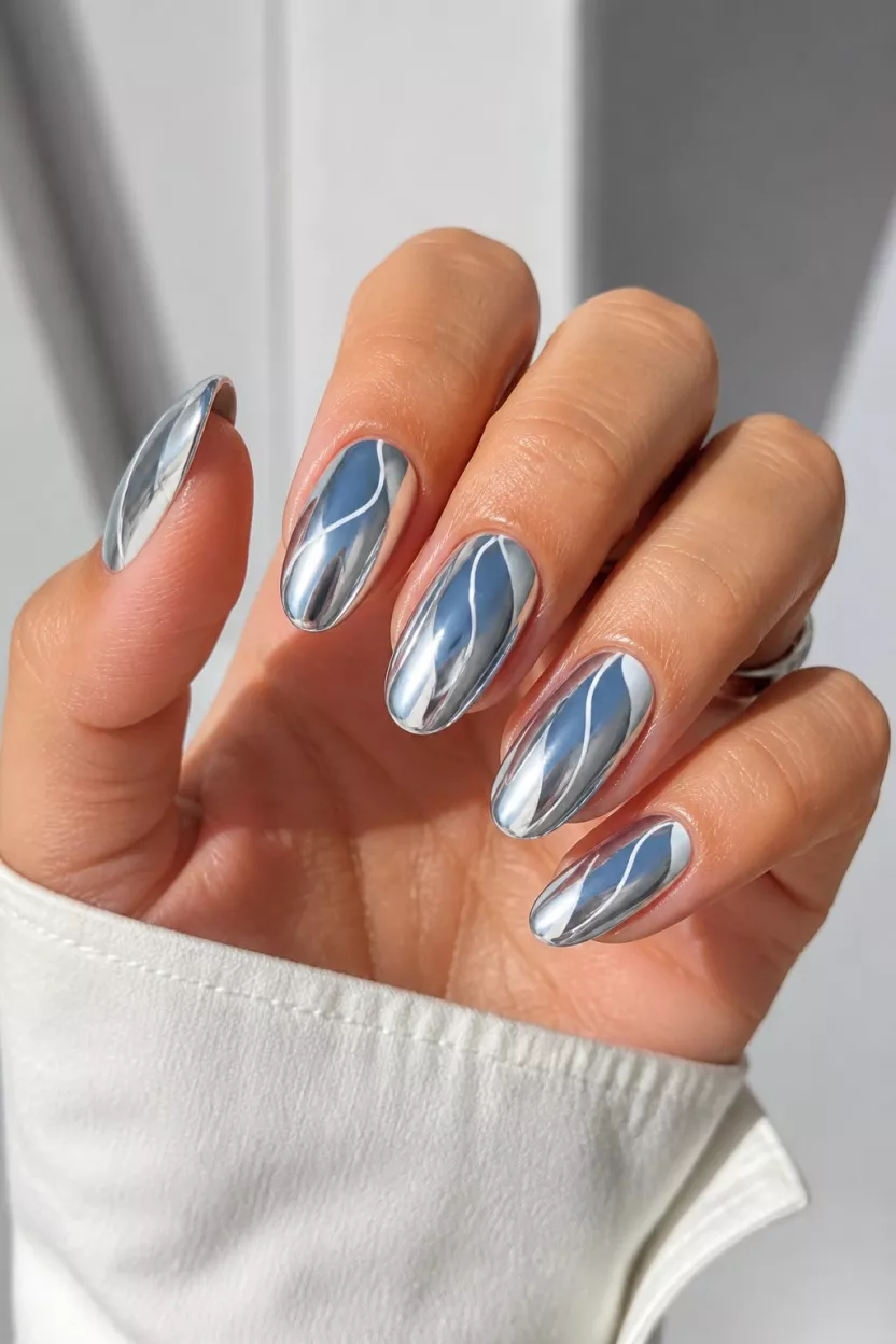 Abstract Chrome Ovals close-up shot of a woman’s hand with five fingers showing nails with sleek oval nails featuring mirror-like chrome finishes and abstract wavy lines in contrasting cool tones, a minimalist modern background.
