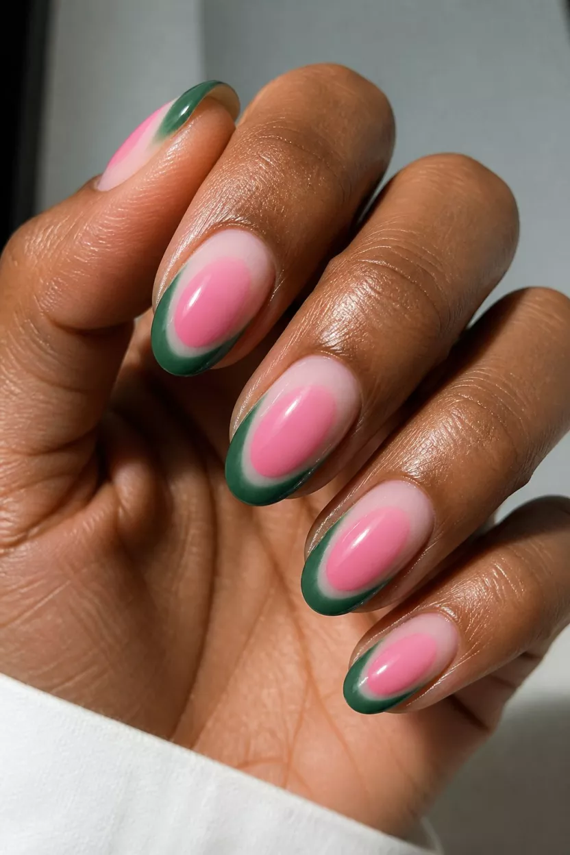 Diffused Pink and Green close-up shot of a woman’s hand with five fingers showing nails with oval nails on dark skin feature a unique design with large, diffused pink oval shapes blending into green tips.
